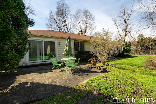 back of house with a lawn, a chimney, and a patio area