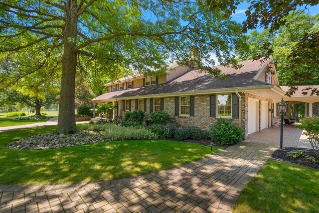 6130 Eidson Rd, Saint Joseph, MI 49085 - view of front of home featuring a garage, driveway, a front yard, stone siding, and a shingled roof