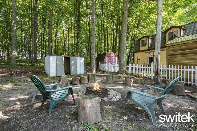 14194 Hicks Lake Rd, Evart, MI 49631 - view of patio / terrace with a fire pit, an outdoor structure, fence, and a storage unit