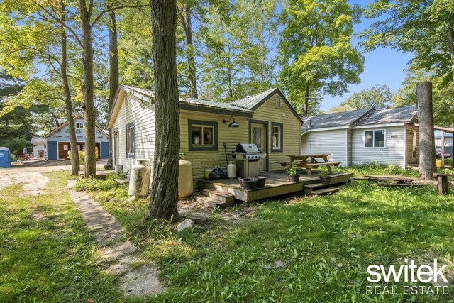 14194 Hicks Lake Rd, Evart, MI 49631 - rear view of house with metal roof, a yard, and a deck