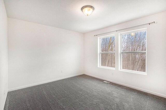 7434 Bramling Dr SE, Caledonia, MI 49316 - spare room featuring visible vents, baseboards, and dark colored carpet