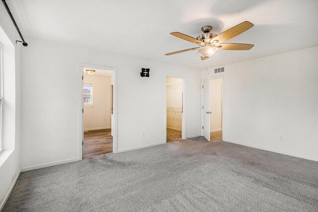 7434 Bramling Dr SE, Caledonia, MI 49316 - unfurnished bedroom with a walk in closet, a ceiling fan, carpet, and visible vents