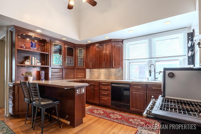 234 Madison Ave SE, Grand Rapids, MI 49503 - kitchen featuring a breakfast bar area, light wood-style flooring, a ceiling fan, and black dishwasher