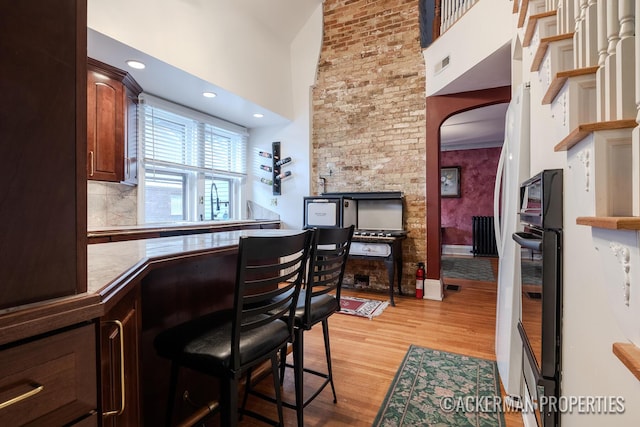 234 Madison Ave SE, Grand Rapids, MI 49503 - interior space with light wood-style floors, a high ceiling, decorative backsplash, and visible vents