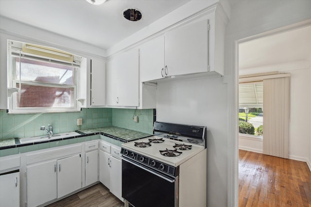 kitchen featuring decorative backsplash, range with gas stovetop, and white cabinetry