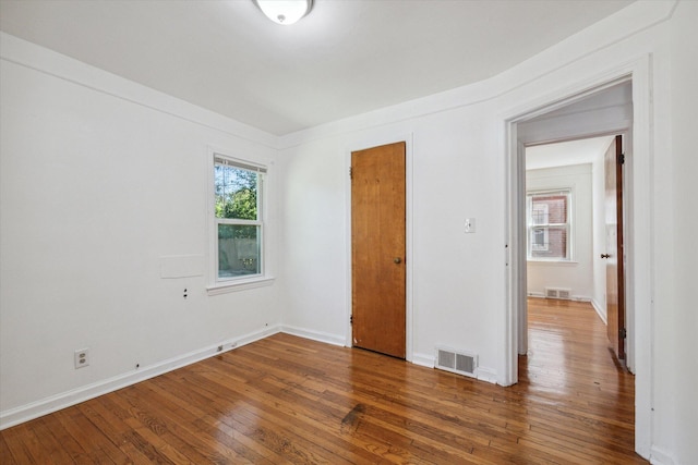 unfurnished bedroom featuring hardwood / wood-style floors, visible vents, and baseboards