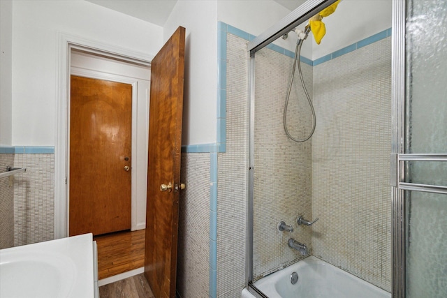 full bath with wainscoting, combined bath / shower with glass door, and wood finished floors