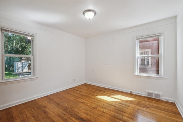 unfurnished room featuring hardwood / wood-style floors, baseboards, and visible vents