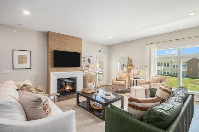 living room featuring light wood-style flooring, recessed lighting, and a glass covered fireplace