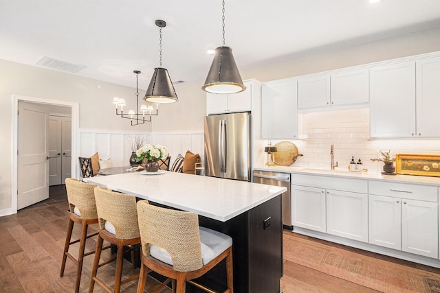 kitchen featuring a notable chandelier, a center island, light countertops, stainless steel appliances, and a sink