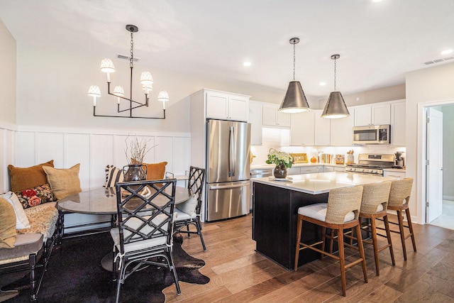 kitchen featuring visible vents, a notable chandelier, wood finished floors, stainless steel appliances, and a kitchen island