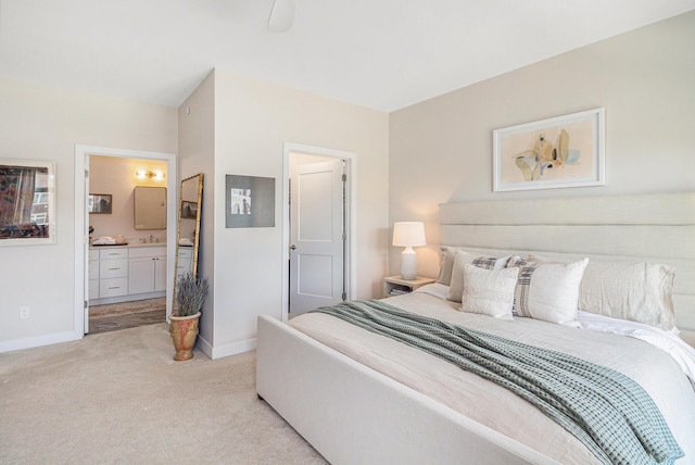 bedroom featuring a sink, ensuite bathroom, light colored carpet, and baseboards
