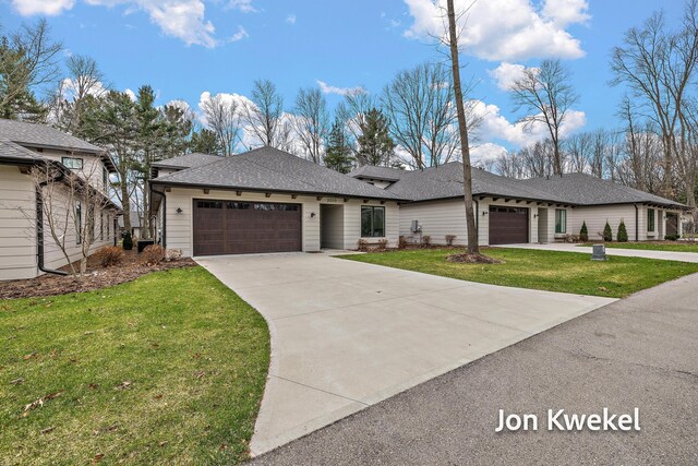 prairie-style home featuring a shingled roof, a garage, concrete driveway, and a front lawn