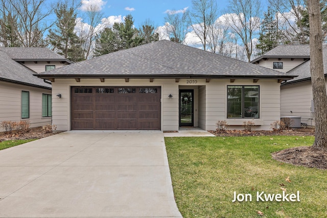 view of front of house featuring a shingled roof, a garage, driveway, and a front lawn