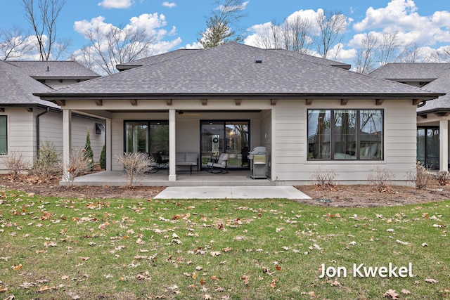 rear view of house featuring roof with shingles, a patio area, a ceiling fan, and a lawn