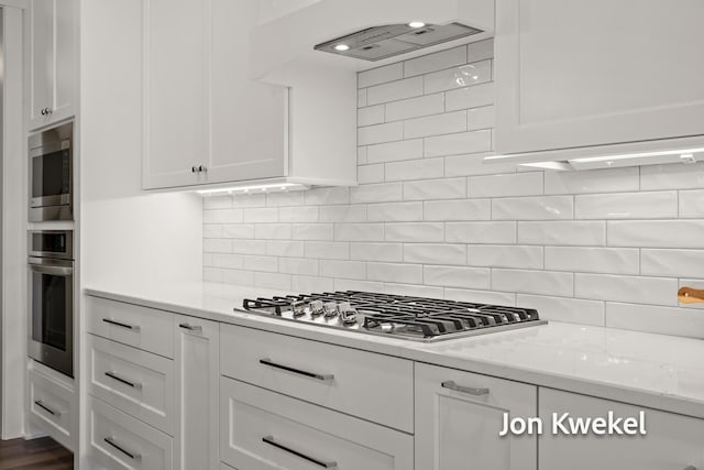kitchen with tasteful backsplash, light stone counters, white cabinetry, and stainless steel appliances