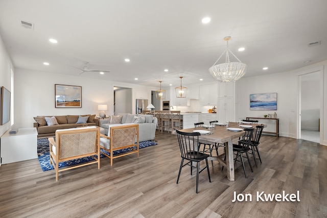 dining room with recessed lighting, visible vents, ceiling fan with notable chandelier, and wood finished floors