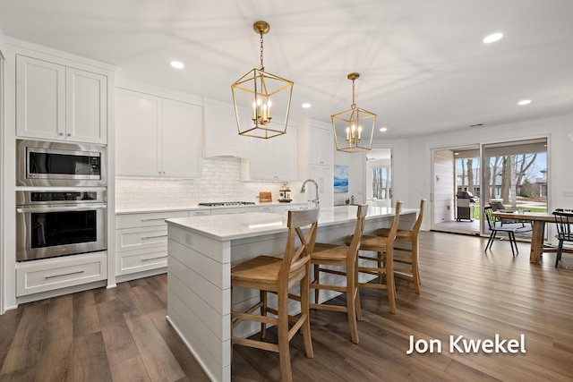 kitchen featuring dark wood-type flooring, tasteful backsplash, a chandelier, stainless steel appliances, and premium range hood