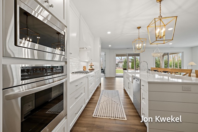 kitchen featuring tasteful backsplash, a chandelier, dark wood finished floors, white cabinetry, and stainless steel appliances