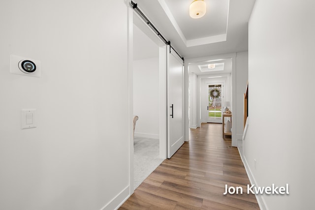 hallway featuring a barn door, baseboards, and wood finished floors