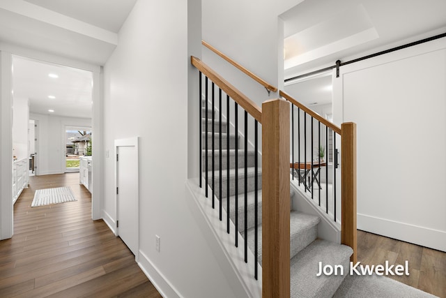 stairway with baseboards, recessed lighting, a barn door, and wood finished floors