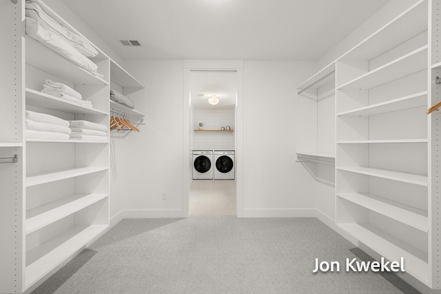 walk in closet with carpet floors, washing machine and clothes dryer, and visible vents