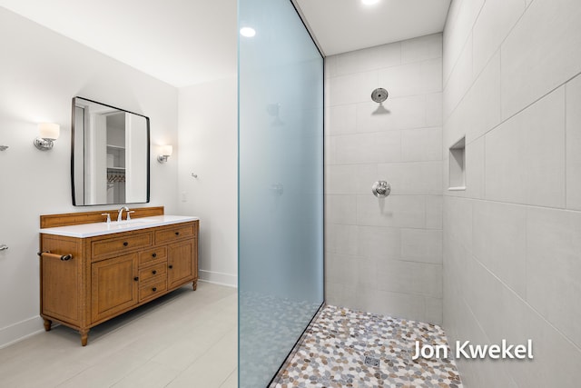 full bathroom featuring a walk in shower, vanity, and baseboards