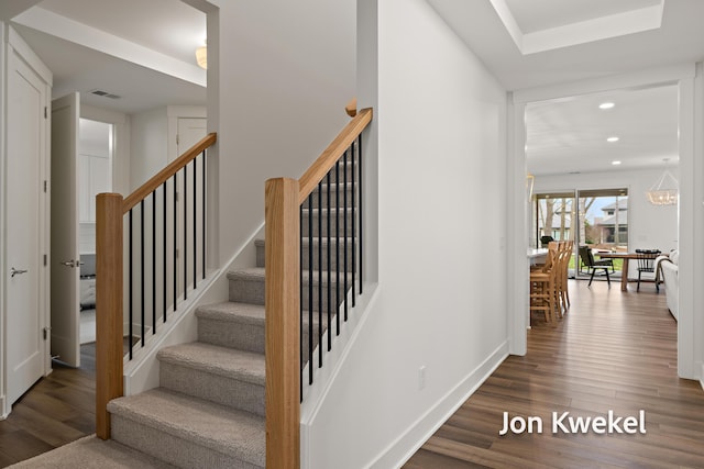 stairway with recessed lighting, visible vents, baseboards, and wood finished floors