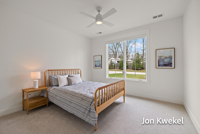 carpeted bedroom with visible vents, baseboards, and a ceiling fan