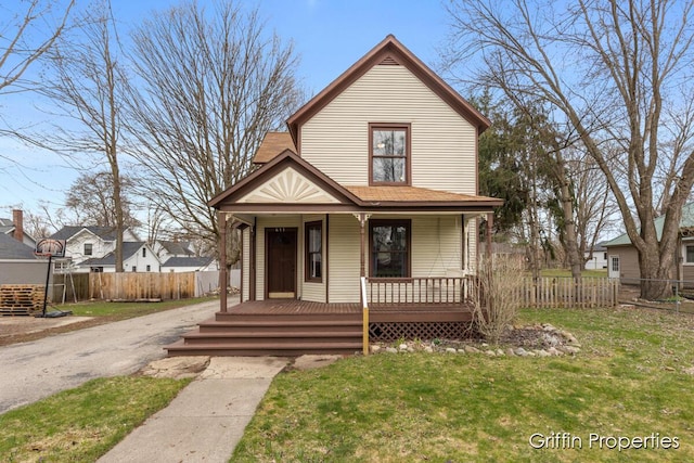 view of front facade with a porch, fence, and a front lawn