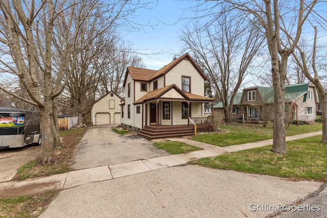 view of front of house featuring a detached garage, a porch, a front lawn, and aphalt driveway