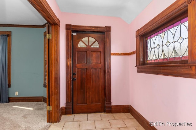 tiled foyer entrance featuring carpet flooring, baseboards, and lofted ceiling