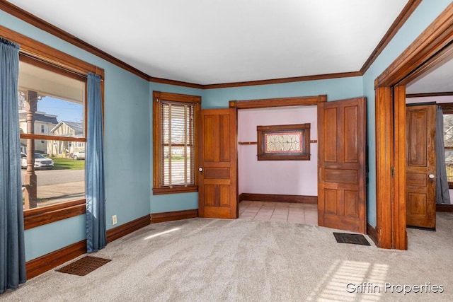 carpeted spare room featuring crown molding and baseboards