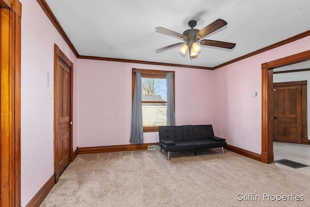 living area with crown molding, ceiling fan, baseboards, and carpet