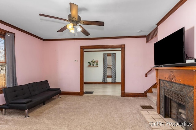 carpeted living area featuring visible vents, a premium fireplace, ornamental molding, and ceiling fan