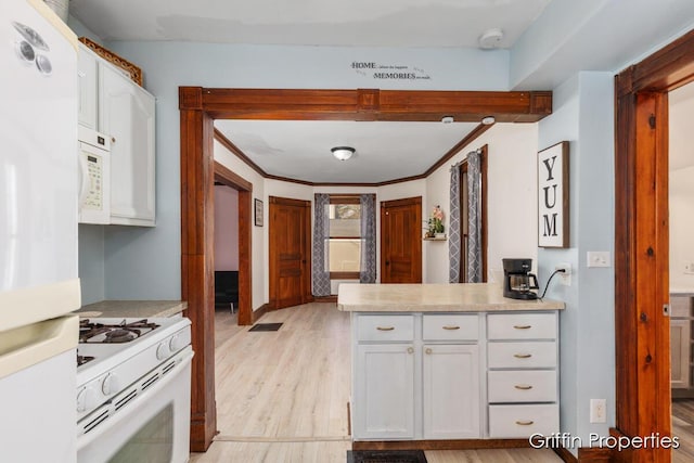 kitchen with white appliances, a peninsula, white cabinetry, light countertops, and light wood finished floors