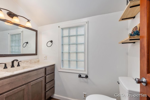 half bathroom featuring toilet, vanity, baseboards, and lofted ceiling