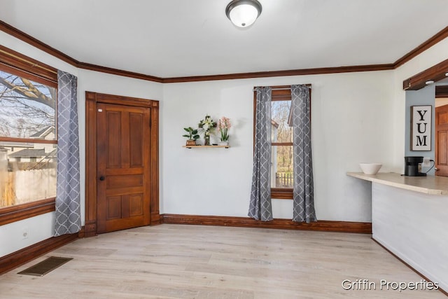 entryway featuring visible vents, baseboards, crown molding, and wood finished floors