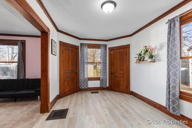 entrance foyer featuring crown molding, visible vents, baseboards, and wood finished floors