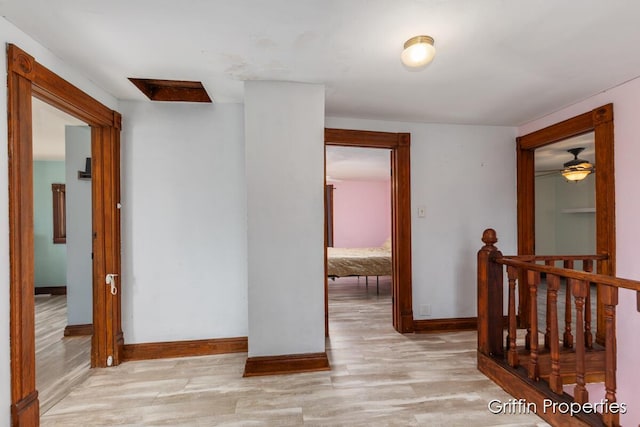 corridor featuring light wood-style floors, baseboards, and an upstairs landing