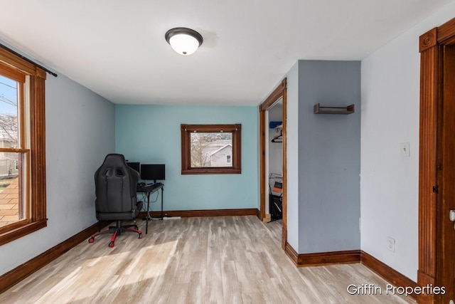 office area with light wood-style flooring, baseboards, and a healthy amount of sunlight