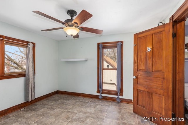 spare room with a wealth of natural light, ceiling fan, and baseboards