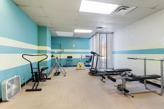 workout area featuring baseboards, visible vents, and a paneled ceiling