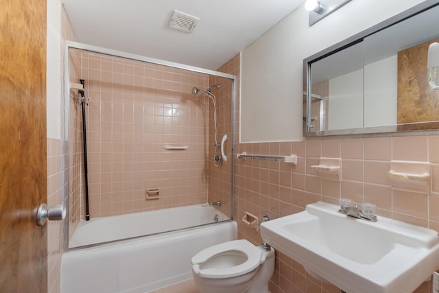 bathroom with a sink, bathtub / shower combination, toilet, tile walls, and visible vents