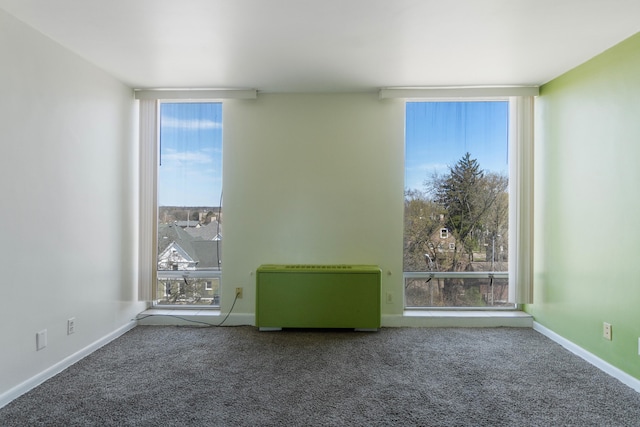 carpeted empty room featuring baseboards and heating unit