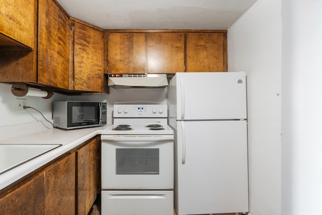 kitchen with brown cabinetry, light countertops, a sink, under cabinet range hood, and white appliances