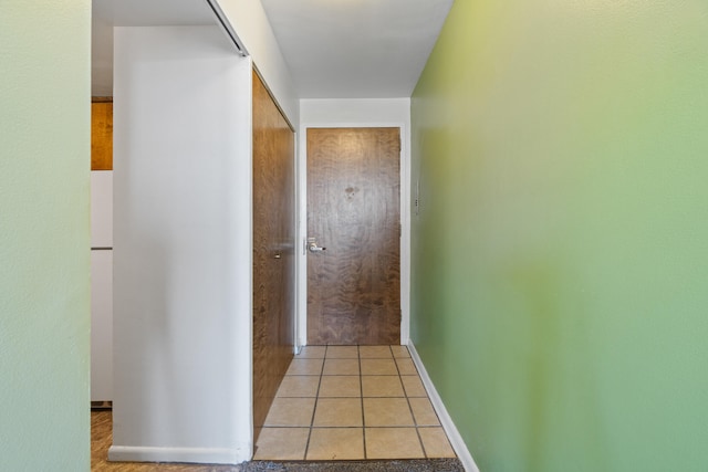 corridor with baseboards and light tile patterned floors
