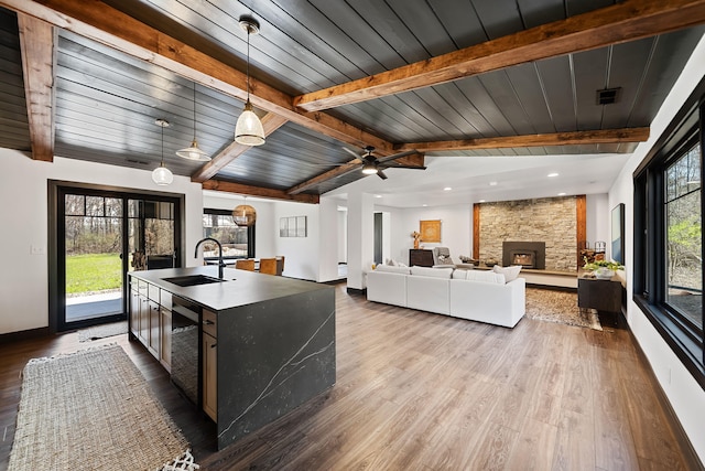 9442 Community Hall Rd, Union Pier, MI 49129 - kitchen featuring lofted ceiling with beams, visible vents, a center island with sink, a sink, and wood finished floors