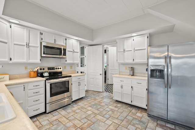 551 W Bridge St, Plainwell, MI 49080 - kitchen with white cabinetry, light countertops, brick patterned floor, and appliances with stainless steel finishes