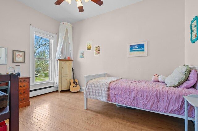 551 W Bridge St, Plainwell, MI 49080 - bedroom with a baseboard radiator, light wood-type flooring, and ceiling fan
